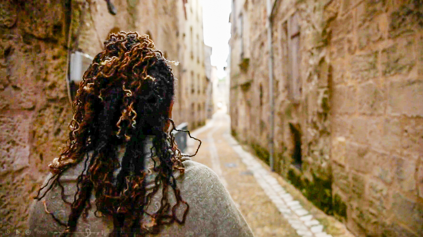 Traciana s'éloignant dans une ruelle pavée